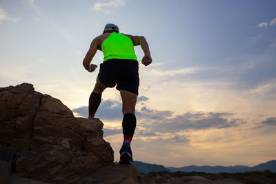 Rear view of man standing on rock against sky