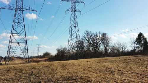 Low angle view of electricity pylon on field