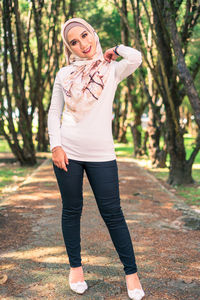 Full length portrait of woman standing against tree