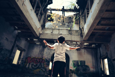 Rear view of boy standing at abandoned building