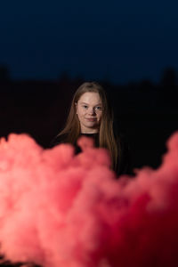 Portrait of a beautiful young woman against black background