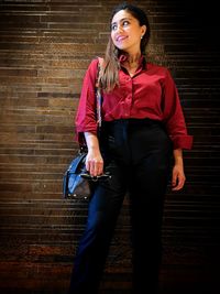 Portrait of young woman standing against wall