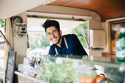 Portrait of happy young entrepreneur standing in food truck