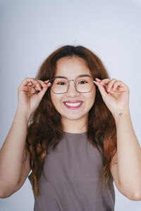 Portrait of smiling young woman wearing eyeglasses against white background