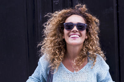 Portrait of smiling woman wearing sunglasses standing outdoors