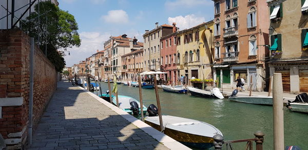 Canal amidst buildings in city against sky