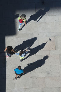 High angle view people walking with shadow on footpath