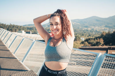 Portrait of young woman looking away against sky