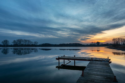 Wooden fishing pier and beautiful evening clouds over the lake