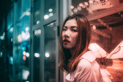 Portrait of woman with redhead against store at night