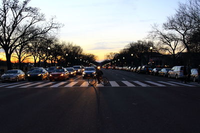 Cars on road against sky during sunset