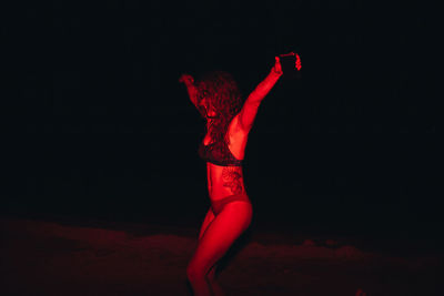 Group of young women having fun at a lakeside party at night with a red light