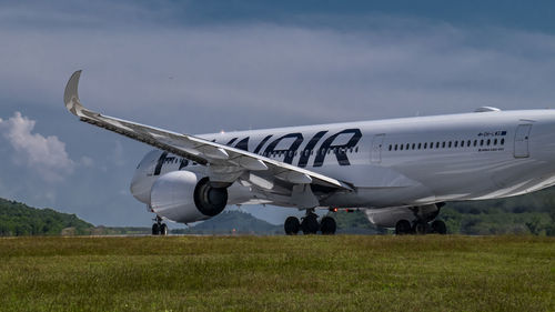 Airplane flying over field against sky