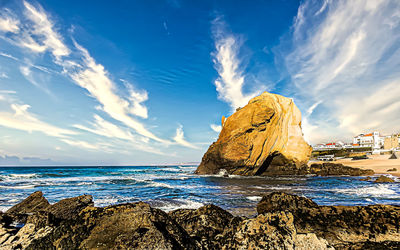 Rock formation on beach against sky