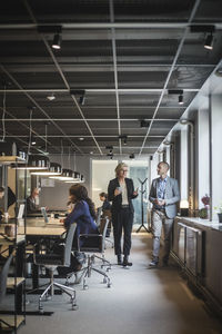 Female entrepreneur discussing with coworker while walking in office