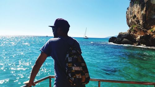 Rear view of man looking at sea against clear sky