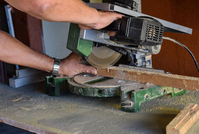 Cropped hands of worker cutting wood in workshop