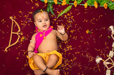 Cute indian boy dresses as lord rama with bow and flowers from top angle