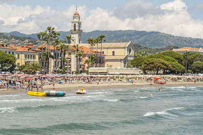 View of buildings by sea against cloudy sky