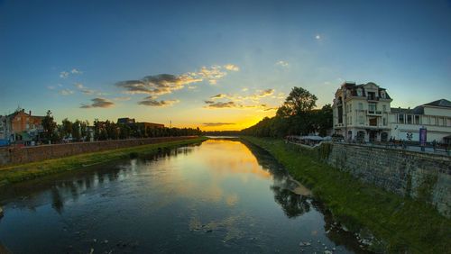 Canal amidst city against sky during sunset