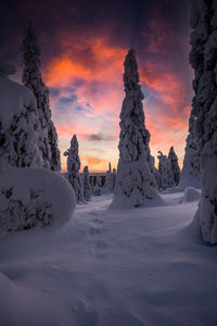 Snow covered landscape against sky during sunset