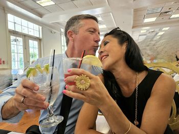 Married gen x diversified couple toasting happiness in restaurant.
