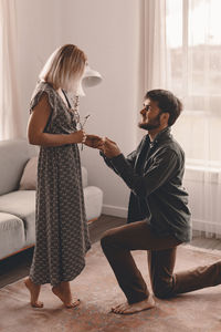 Smiling man proposing girlfriend at home