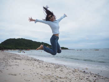 Full length of happy woman jumping at beach