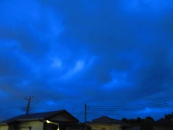 Low angle view of silhouette buildings against blue sky