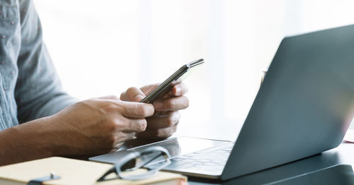 Midsection of businessman using laptop on table