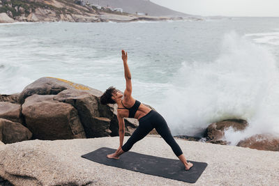 Side view of woman standing on rock at beach