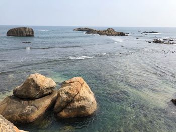 Scenic view of rocks in sea against clear sky