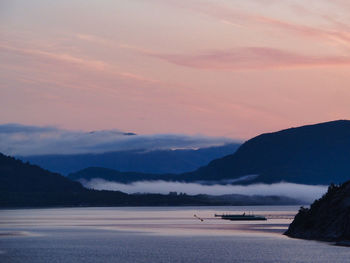 Scenic view of sea and mountains against sky at sunset