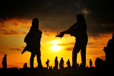 Silhouette people standing against sky during sunset