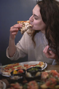 Close-up of woman eating pizza at table