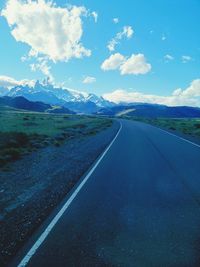 Road leading towards mountains against sky