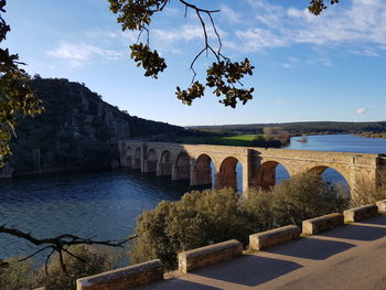 Arch bridge over river against sky