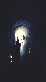 Silhouette people walking in illuminated tunnel