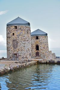 Old building by sea against sky