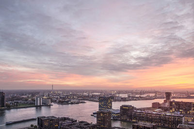 Aerial view of river and cityscape against cloudy sky during sunset