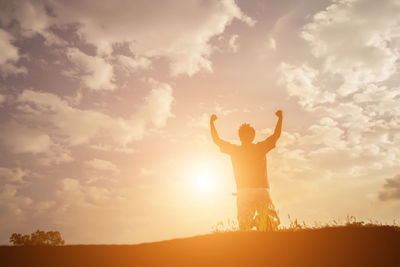 Silhouette man standing on field against sky during sunset