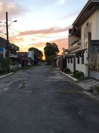 Road leading towards city against sky at sunset