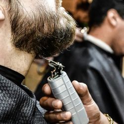 Cropped hand shaving man beard with electric razor