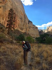 Woman looking up while standing on field against rock formation