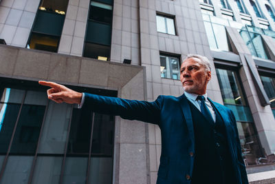 Portrait of young man standing against building