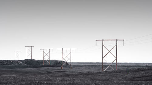 Electricity pylon on field against clear sky