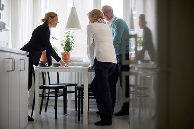 Smiling estate agent and senior couple discussing over documents of new house