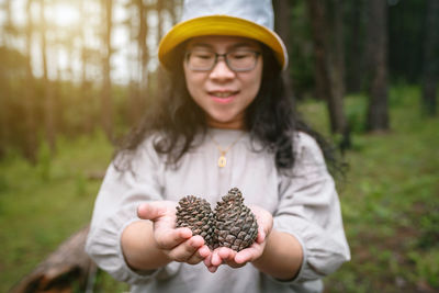 Portrait of woman holding hat in forest