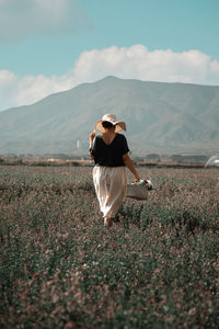 Rear view of woman standing on field against sky