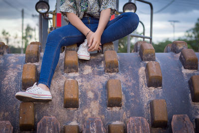 Low section of woman sitting on metal